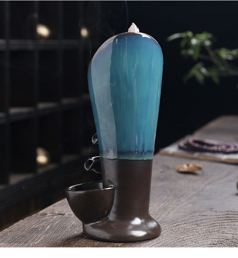 Full rear view of the glossy blue and brown incense burner with a cone visible above the curved back.