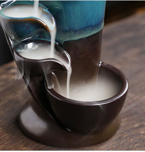Close-up of the lowest dark bowl on the blue waterfall burner, filled with smoke from the channel above.