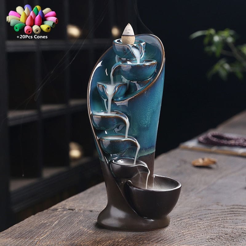 Blue backflow incense burner with smoke cascading down its bowls and an inset showing 20 included incense cones.