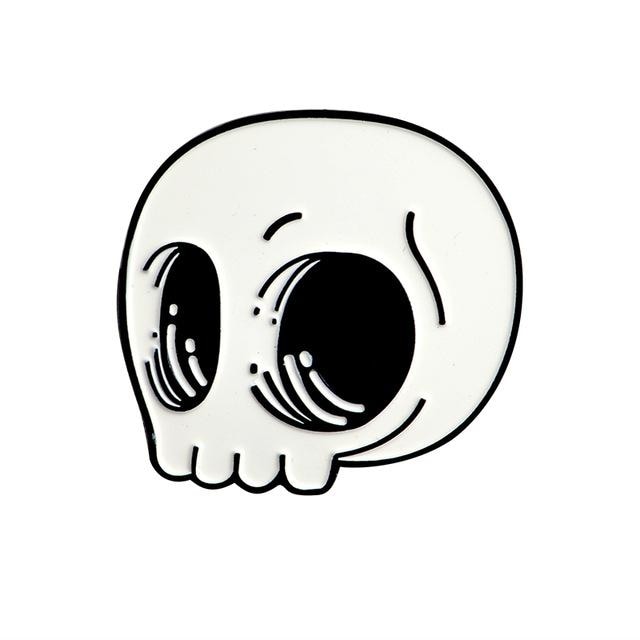 White cartoon skull enamel pin isolated on white, with oversized black eye sockets, curved highlights and a rounded outline.
