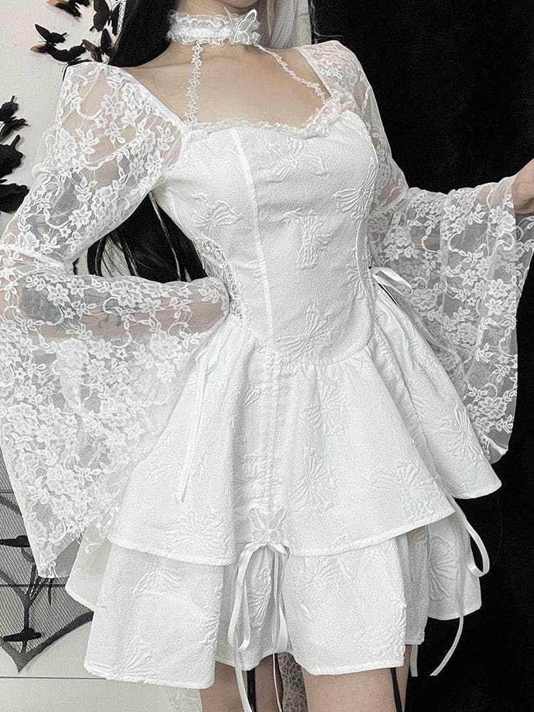 Three-quarter front view of the white dress with one hand on the hip, showing its fitted waist, shoulder lace and layered butterfly-textured skirt.