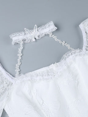 White dress neckline laid flat on a gray background, with its lace choker connected by narrow star-patterned straps above the scalloped bodice edge.