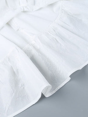 Close view of overlapping white skirt layers and the raised butterfly pattern, showing the curved edges and texture of the fabric.