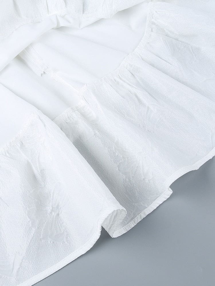 Close view of overlapping white skirt layers and the raised butterfly pattern, showing the curved edges and texture of the fabric.
