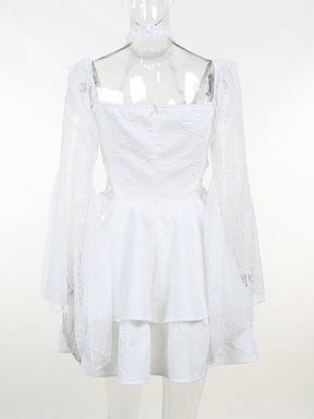 Rear view of the white dress on a clear mannequin, showing the fitted bodice, long lace sleeves and layered hem.