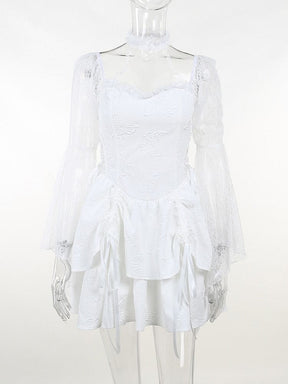 Front view of the white dress on a clear mannequin. Star-patterned choker straps, floral lace sleeves and butterfly details stand out above the layered skirt.