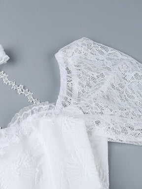 Close-up of the white dress shoulder and sleeve, showing the floral lace pattern and scalloped edging beside the textured bodice fabric.