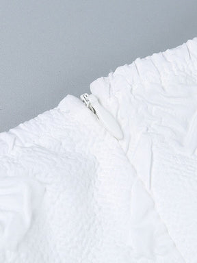 Close-up of the white dress zipper and surrounding seams, showing the concealed-style fastening against textured fabric.