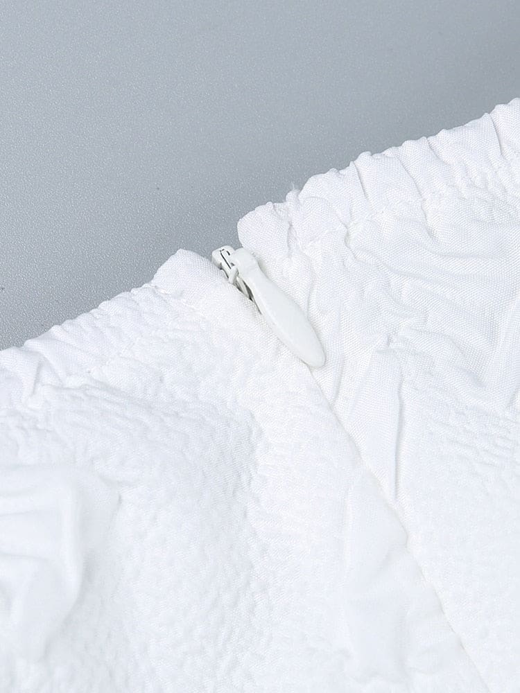 Close-up of the white dress zipper and surrounding seams, showing the concealed-style fastening against textured fabric.