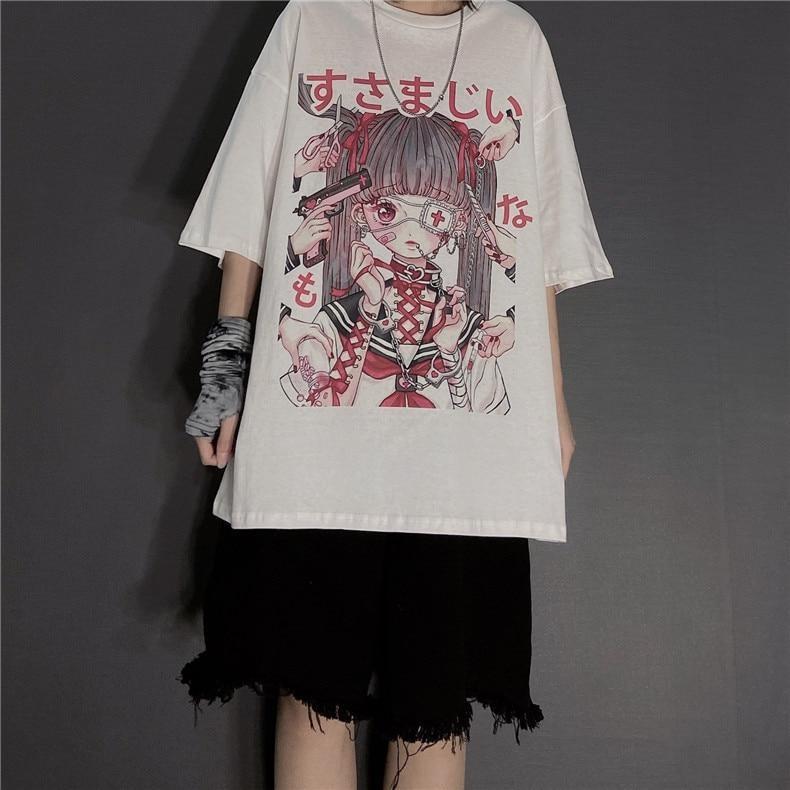 White oversized anime graphic T-shirt styled with frayed black shorts, a long necklace and a patterned wrist covering against a gray wall.