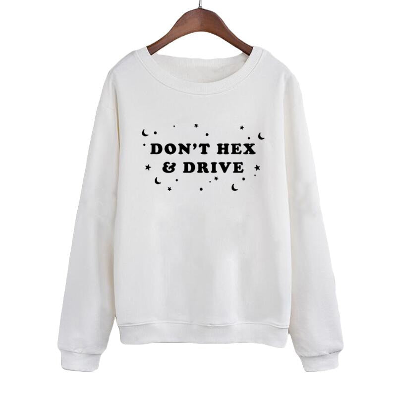 White crewneck sweatshirt on a wooden hanger, with black DON’T HEX & DRIVE lettering surrounded by crescent moons, stars and dots. Long sleeves end in ribbed cuffs above a matching ribbed hem.