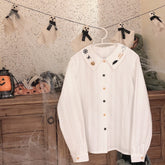 Full white Halloween blouse on a hanger, showing the embroidered collar, long gathered sleeves, buttoned cuffs and contrasting front buttons.