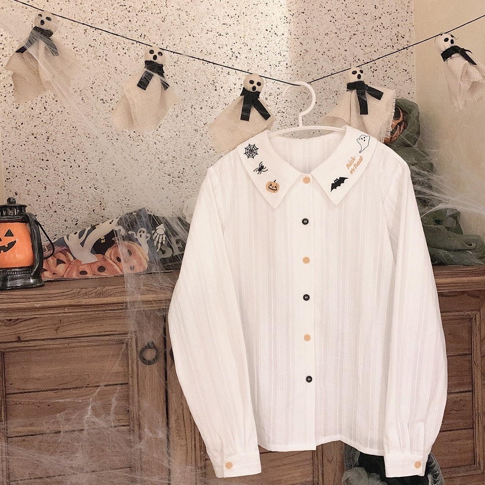 Full white Halloween blouse on a hanger, showing the embroidered collar, long gathered sleeves, buttoned cuffs and contrasting front buttons.