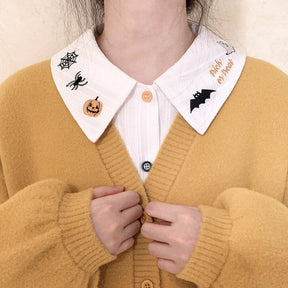 White Halloween collar and blouse front layered beneath a mustard cardigan, showing the contrasting embroidery on both collar points.