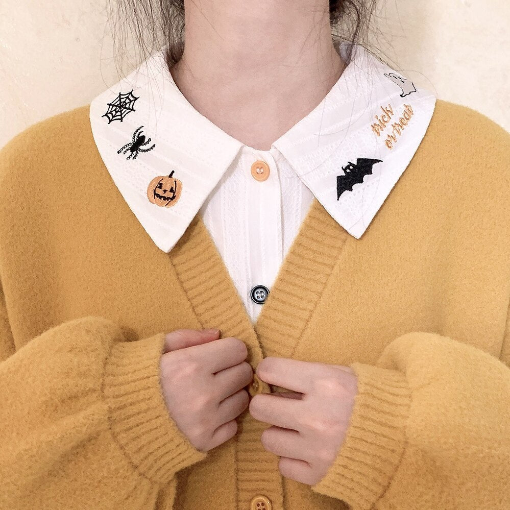 White Halloween collar and blouse front layered beneath a mustard cardigan, showing the contrasting embroidery on both collar points.