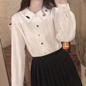 White embroidered-collar blouse tucked into a black pleated skirt, with a long sleeve lifted to show the gathered cuff and textured fabric.