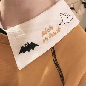 Close-up of the opposite white collar point, showing a small outlined ghost, black bat and gold Trick or Treat embroidery.