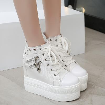 White skull zipper platform sneakers shown close up from the front on a tiled floor.