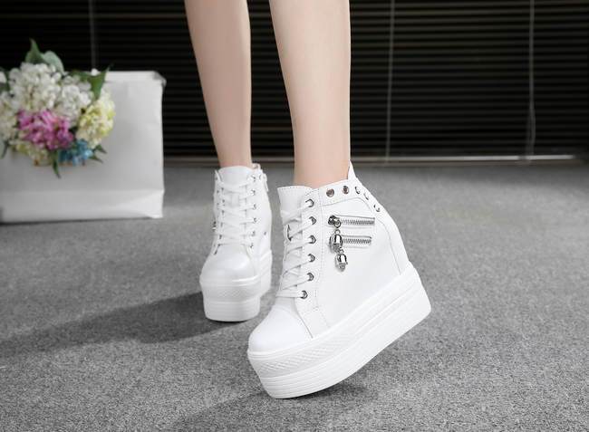 White high-top platform sneakers shown from the front and outer side beside a flower box.