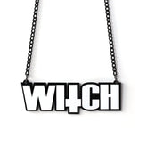 Black and white acrylic WITCH lettering necklace on a black chain, with an inverted-cross shape incorporated into the word.
