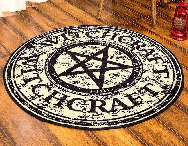 Round pentagram rug displayed on a floor beside a chair, with its dark bound edge and printed lettering visible.