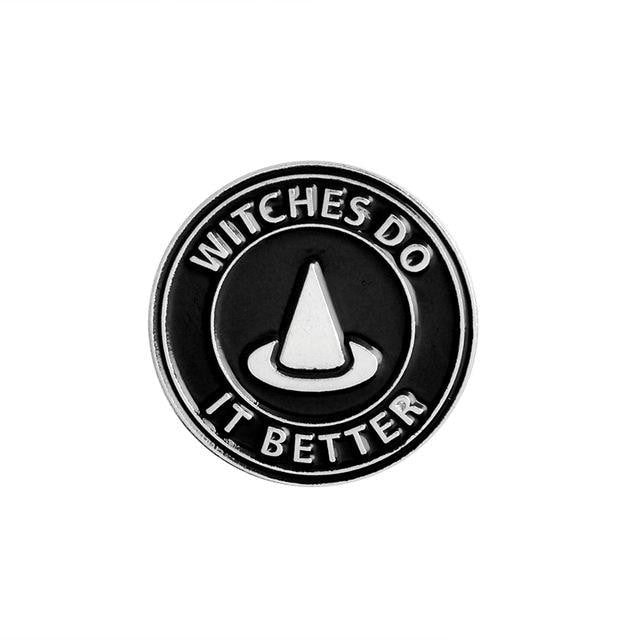 Round black enamel pin with a pointed witch hat and the silver-tone slogan Witches Do It Better.