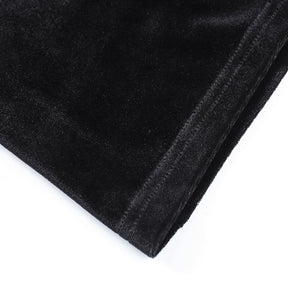 Detail of the gown's stitched hem and softly reflective black velvet surface.