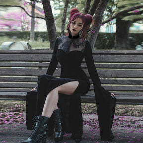 The Witching gown styled with black boots while seated beneath a tree, showing lace shoulders and a flowing skirt.
