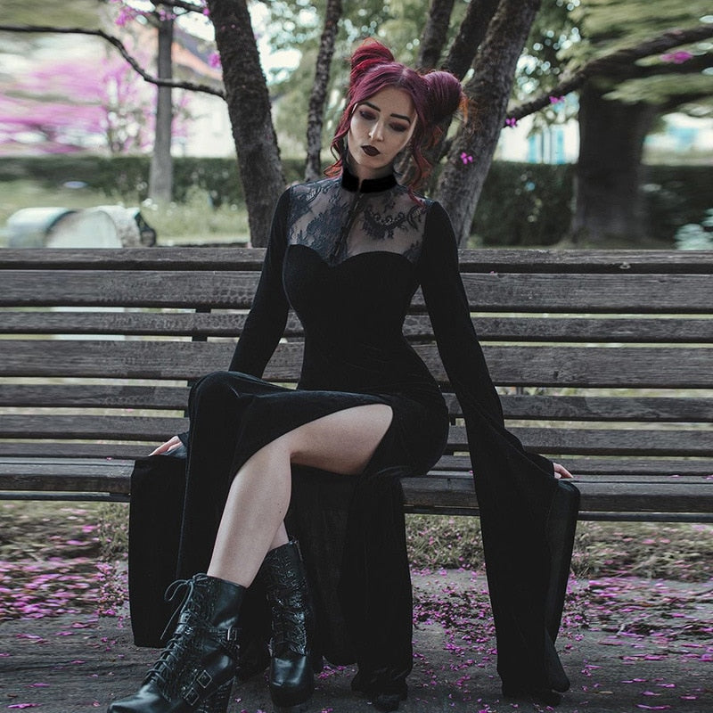 The Witching gown styled with black boots while seated beneath a tree, showing lace shoulders and a flowing skirt.