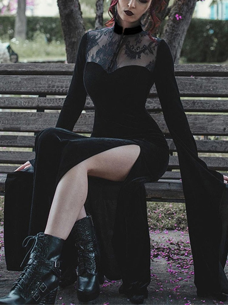 Black velvet gothic gown worn on a wooden bench, showing a floral lace yoke, high slit and deeply draped sleeve.