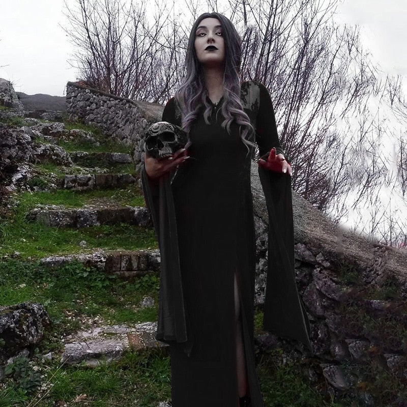 Black gothic gown worn on stone steps with a skull prop, showing sweeping sleeves and a floor-length skirt.