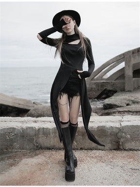 Front view of a black split-front layering dress with hand-covering sleeves and long pointed tails, styled with shorts, knee-high boots and a black hat.