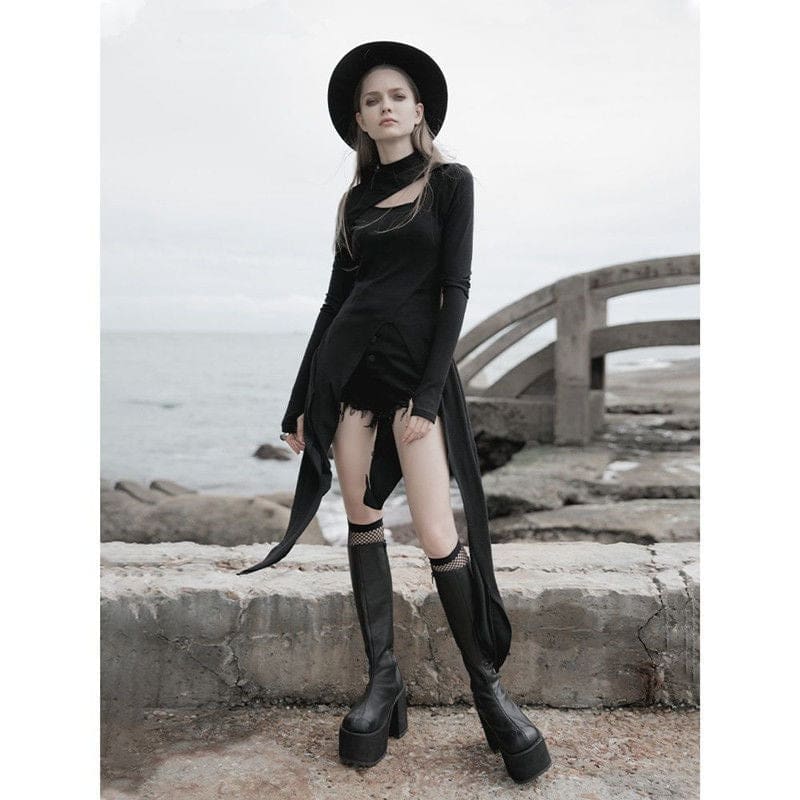 Black witchy layering dress shown beside a stone seaside railing, with uneven pointed panels framing separate black shorts.