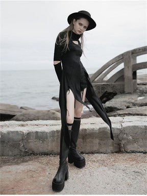 Angled coastal view of a black asymmetric tunic worn over shorts, showing the open front and long narrow hem panels.