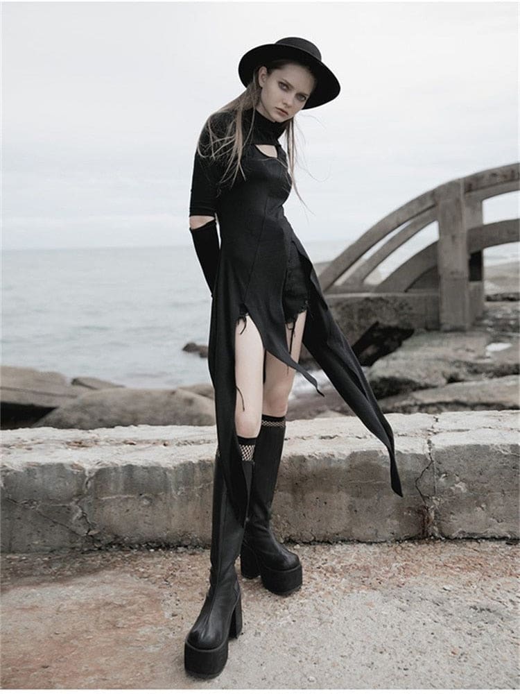Angled coastal view of a black asymmetric tunic worn over shorts, showing the open front and long narrow hem panels.