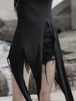 Close-up of the black layering dress opening at the front waist, with pointed panels falling on either side of separate distressed shorts.