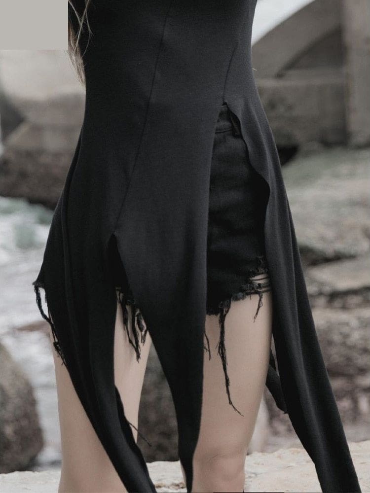 Close-up of the black layering dress opening at the front waist, with pointed panels falling on either side of separate distressed shorts.