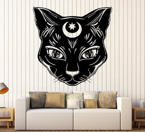 Black witchy cat-face decal displayed above a sofa in a living-room mockup, with detailed eyes and a small celestial forehead motif.