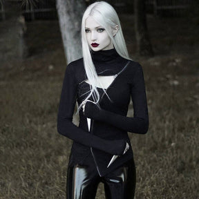 Black cutout turtleneck styled with glossy trousers, shown with crossed arms and its high collar folded around the neck.