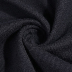 Close-up of black knit fabric arranged in a swirl, showing the surface texture of the turtleneck top.
