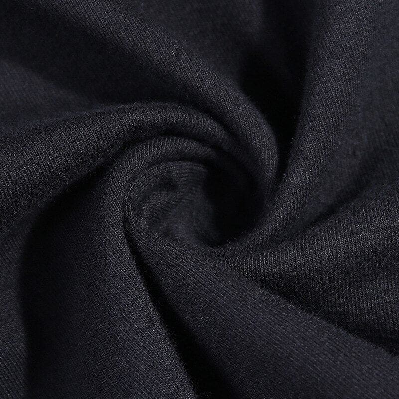 Close-up of black knit fabric arranged in a swirl, showing the surface texture of the turtleneck top.
