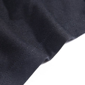 Close-up of the black top’s folded hem and parallel stitching.