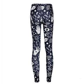Rear view of black witchy leggings with the white celestial and palmistry print continuing from the waist to the narrow ankles.