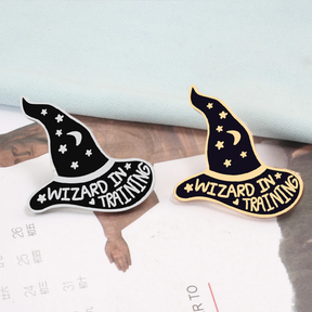 Purple Wizard in Training hat pins arranged together on printed paper, showing both metallic finishes.
