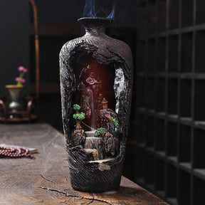Red light illuminates the inner landscape of the vase-shaped incense burner against a darker background.