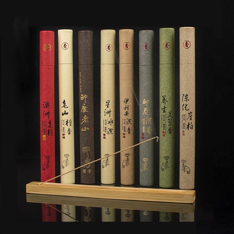 Earthy incense tubes arranged behind a wooden holder on a black background, showing the different paper colours and Chinese labels.