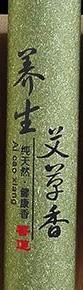 Detail of the green wormwood incense tube with black Chinese lettering and a small red seal.