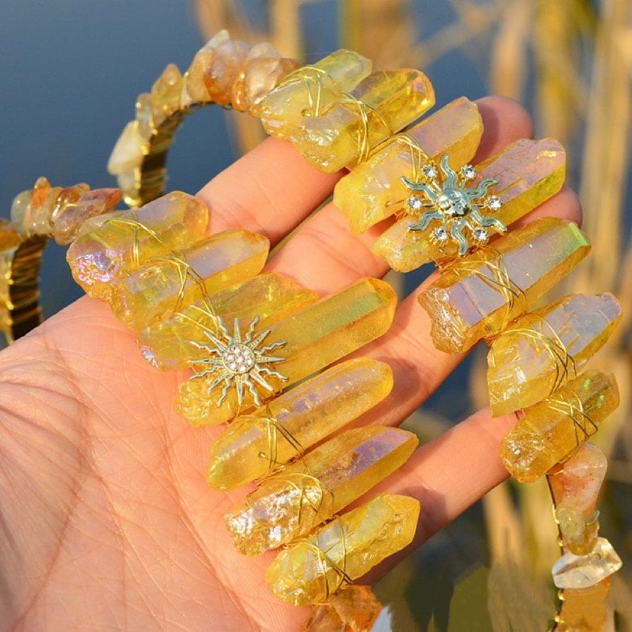 Two yellow crystal tiaras held together, showing the Sun Face and Sunburst gold-tone emblems side by side.