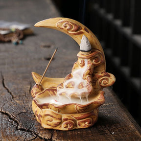 Front three-quarter view of the Yellow moon incense burner on weathered wood, showing a lit cone above the pale smoke gathered in the basin.