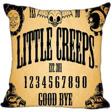 Yellow square cushion cover with large black decorative lettering, numbers and Good Bye, framed by a winged skull, sun and crescent moon illustrations.